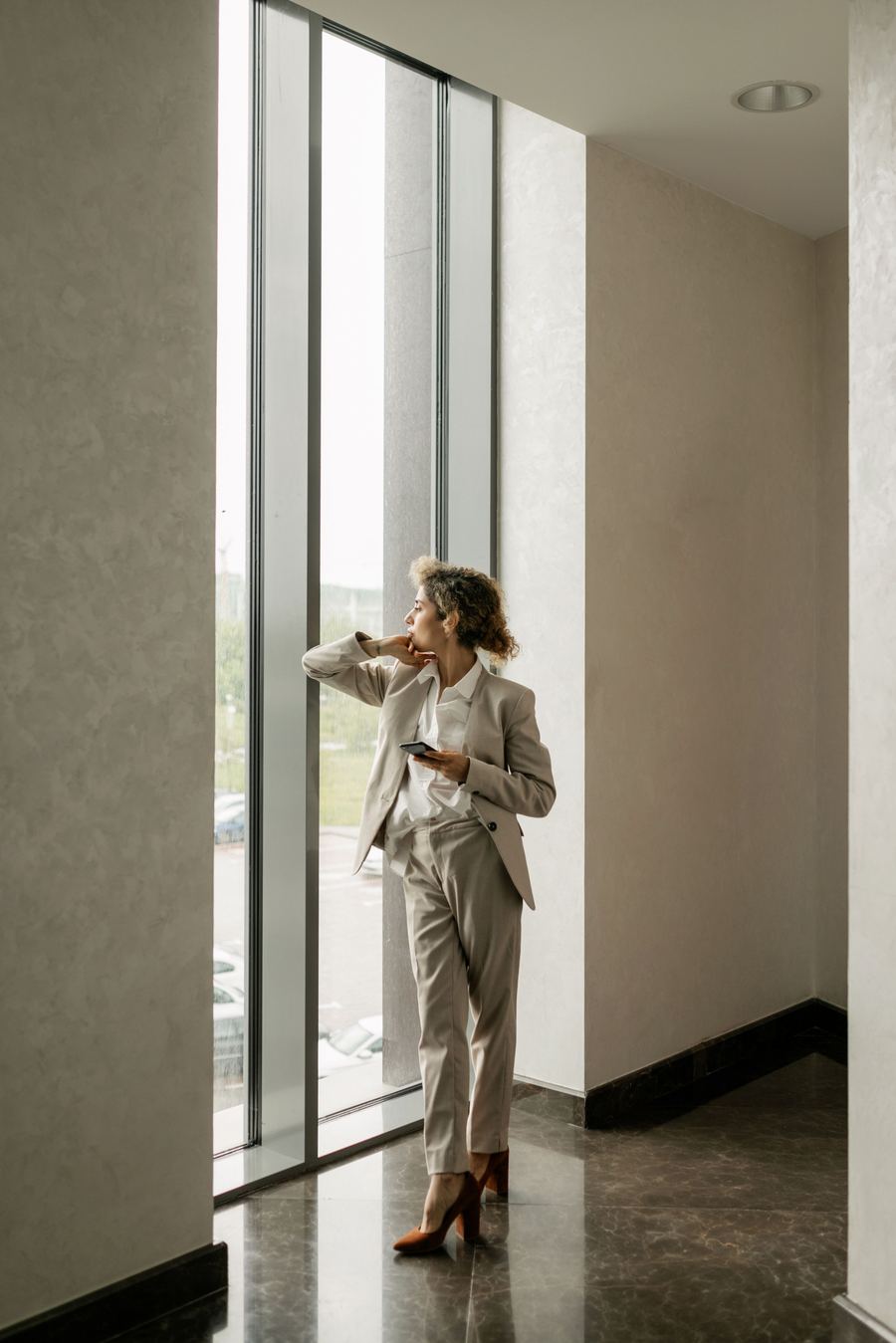 A professional by a full-height window in a calm, minimal studio interior